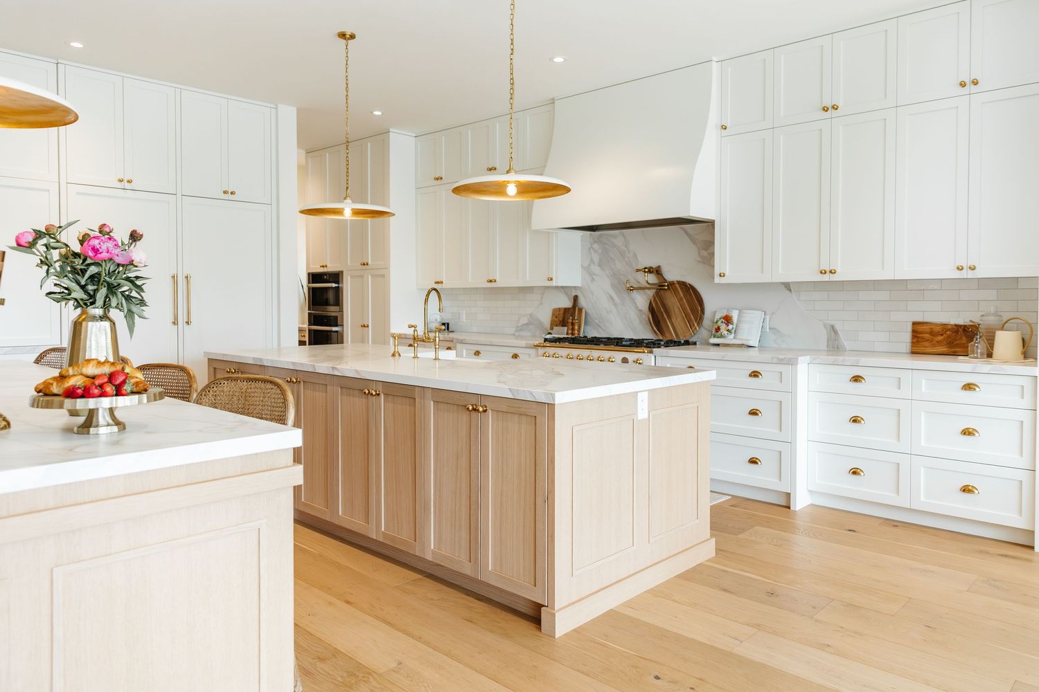 Expansive white kitchen with wood accents, large island, and abundant natural lighting in a west Kelowna Airbnb