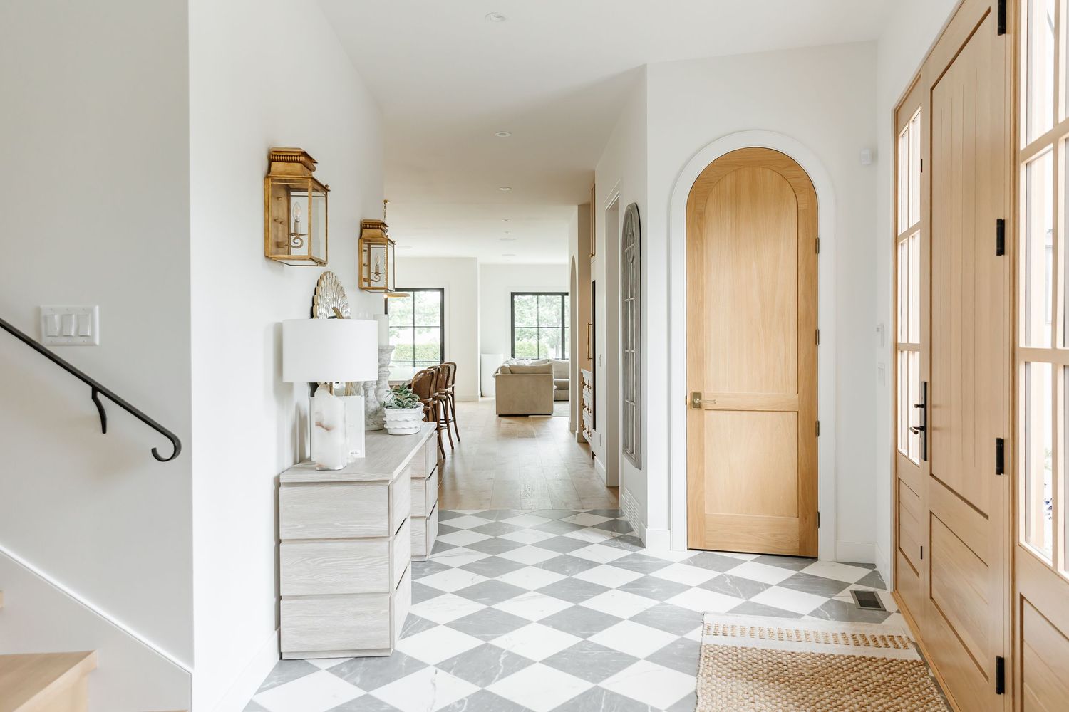 Long corridor with black and white checkered flooring and bright white walls illuminated by natural light in a west Kelowna Airbnb