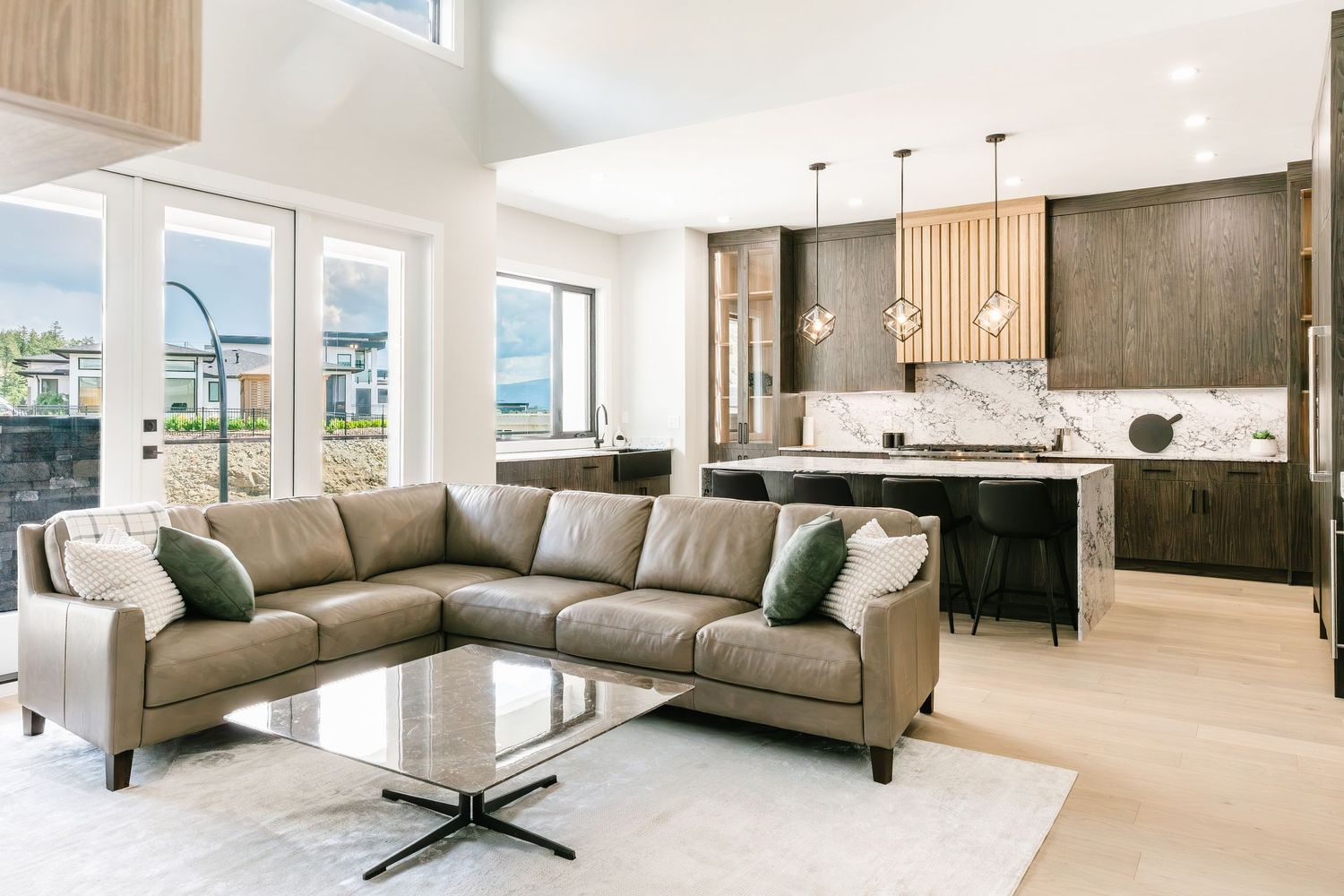 Modern living room with gray sectional sofa and large windows offering panoramic views  in a west Kelowna Airbnb