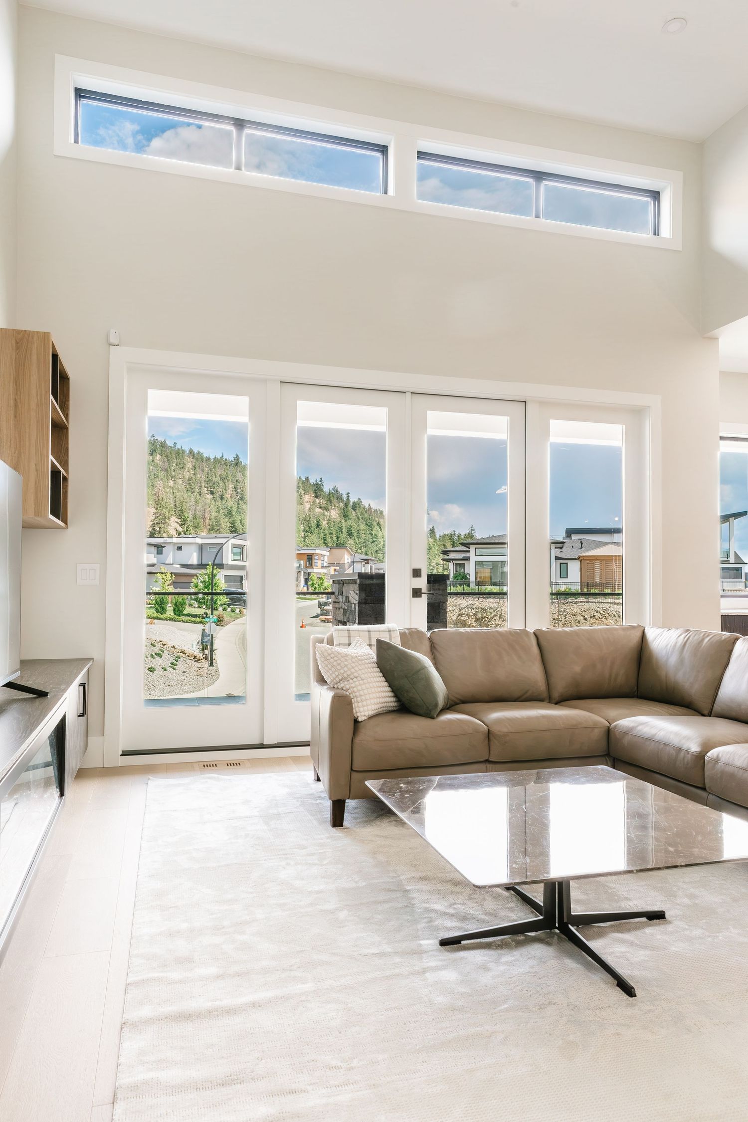Spacious contemporary living area with high ceilings and floor-to-ceiling windows overlooking mountains  in a west Kelowna Airbnb