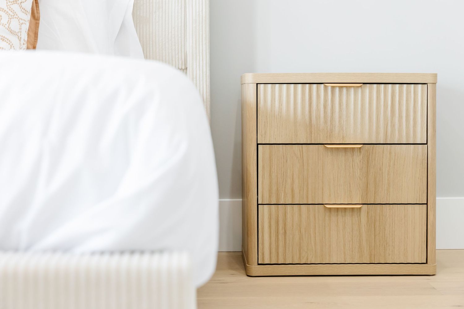Clean white bedroom interior with natural wood furniture and crisp bedding in a west Kelowna Airbnb