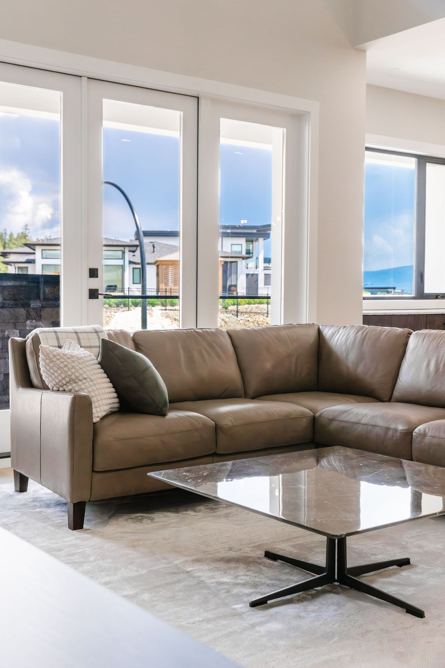 Luxurious airbnb living room with brown leather sectional and large windows offering scenic views in West Kelowna