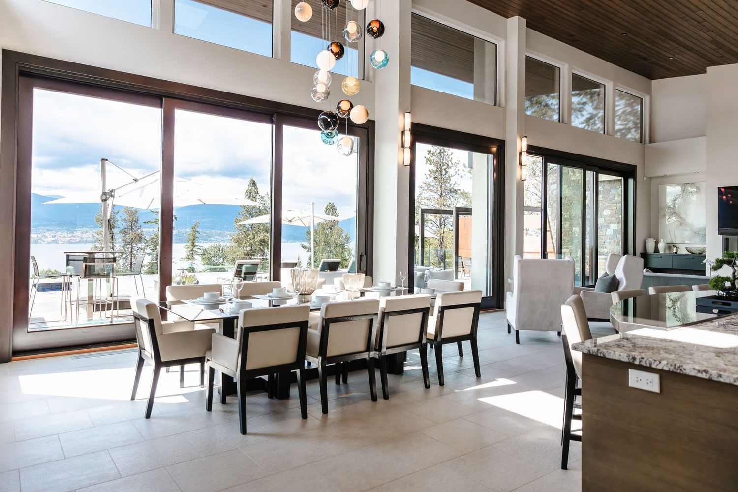 Expansive open-concept dining area with wood ceiling beams and floor-to-ceiling windows.