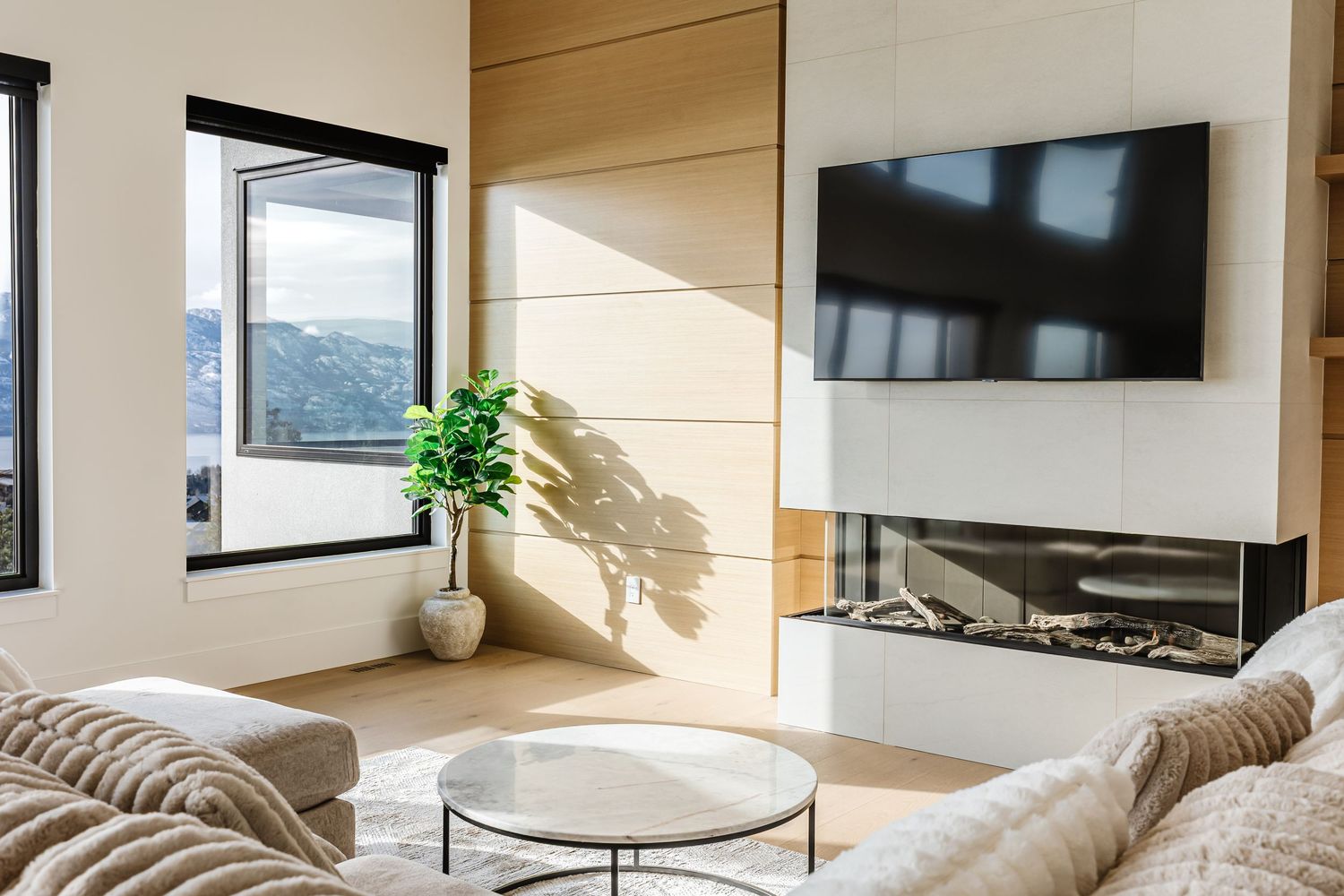 Modern apartment interior with floor-to-ceiling windows, sleek furniture, and natural light illuminating the open living space.