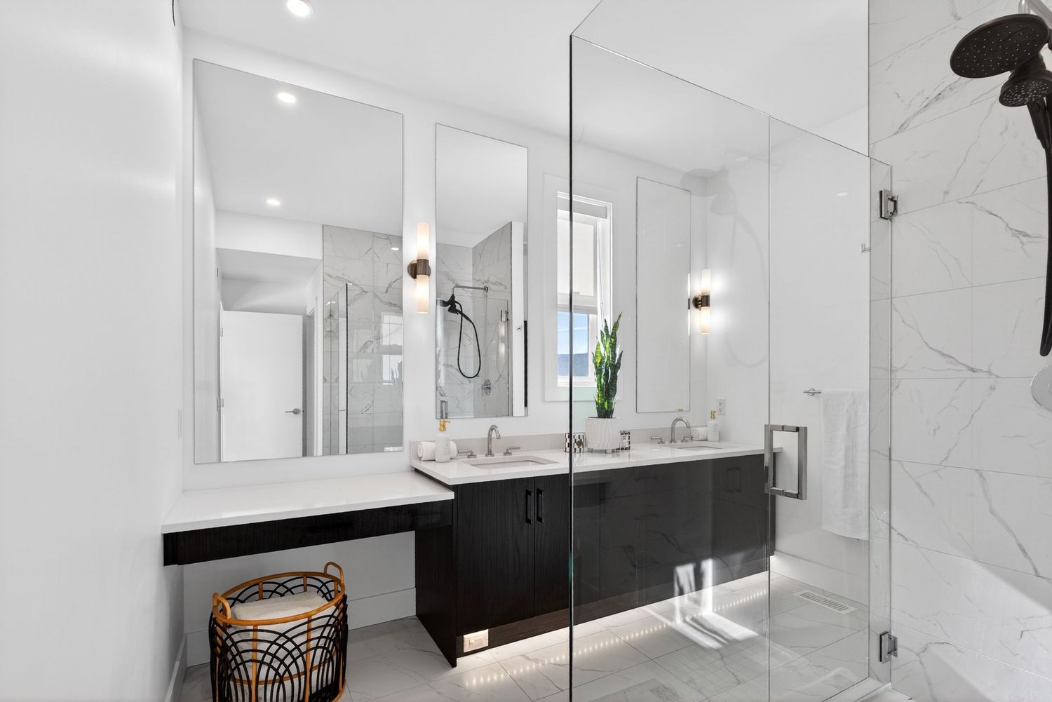 Modern bathroom with black vanity, dual sinks, large mirrors, marble walls, and glass shower enclosure.
