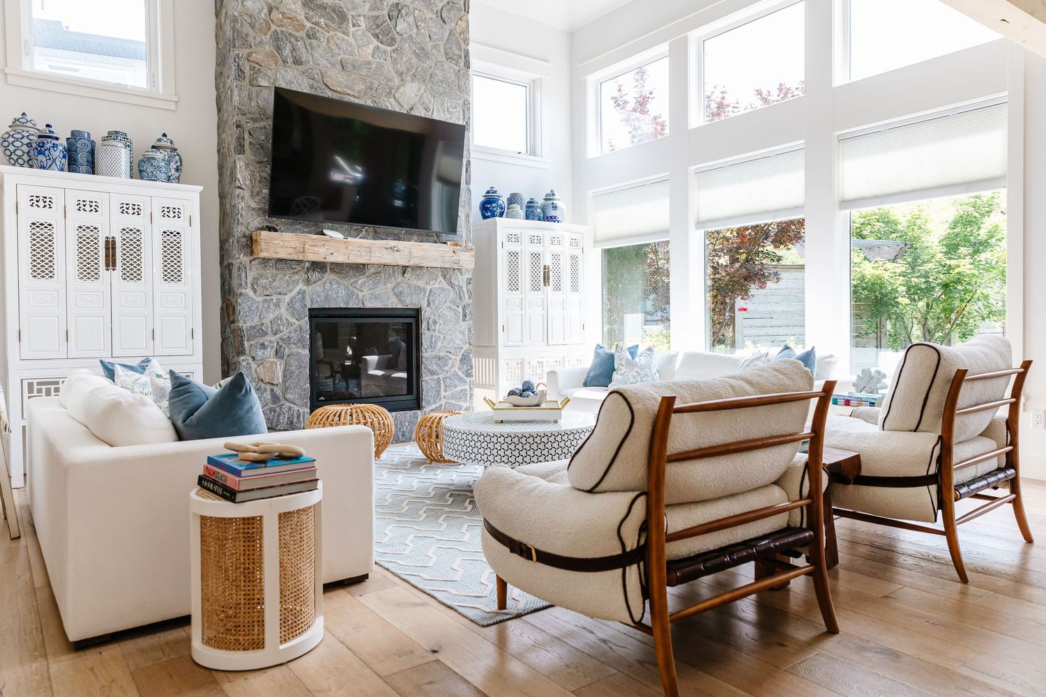 Luxurious living room with stone fireplace, coastal decor, and panoramic windows offering abundant natural light.