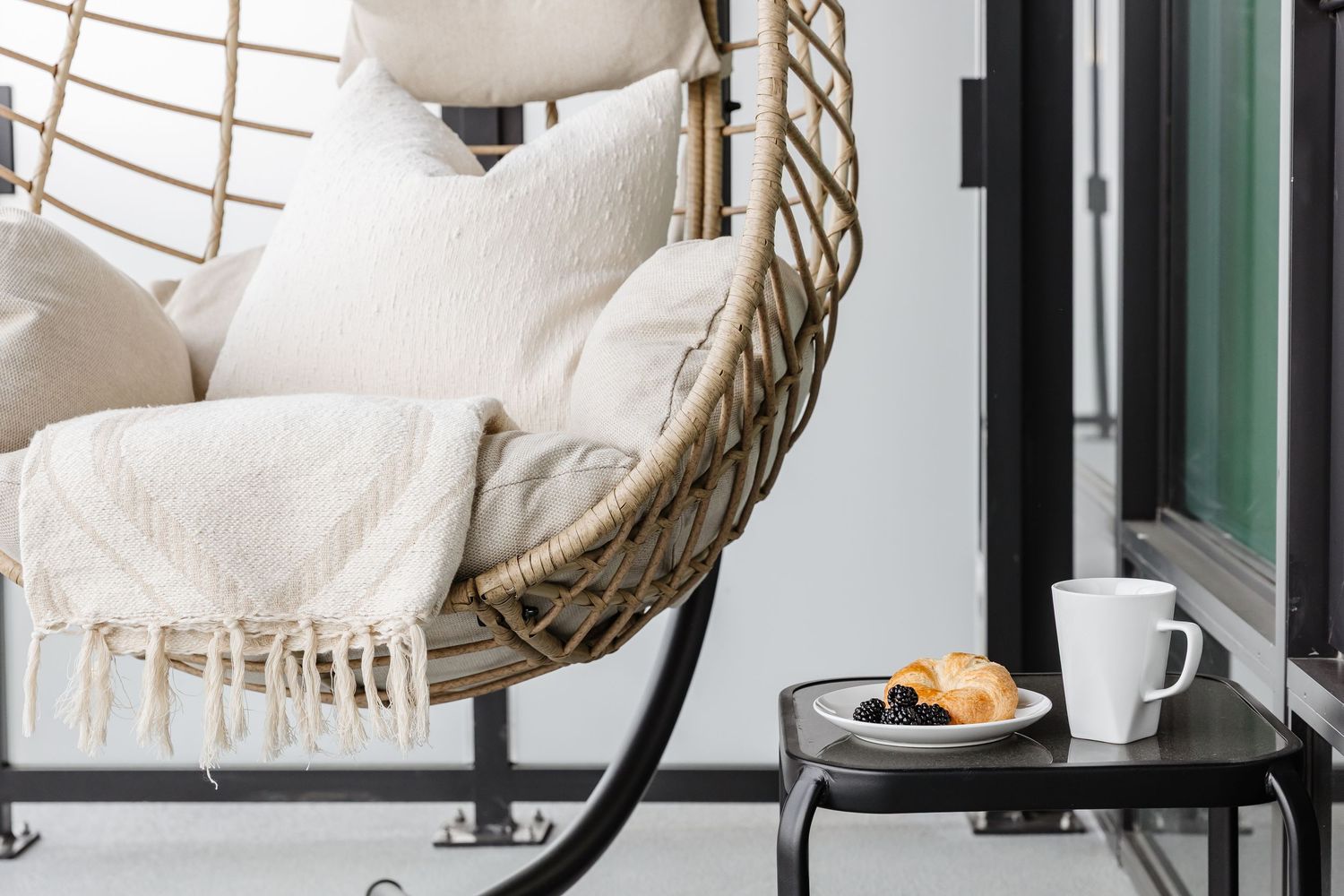 Cozy living room corner with white armchair, round side table, and hanging rattan pendant light fixture.