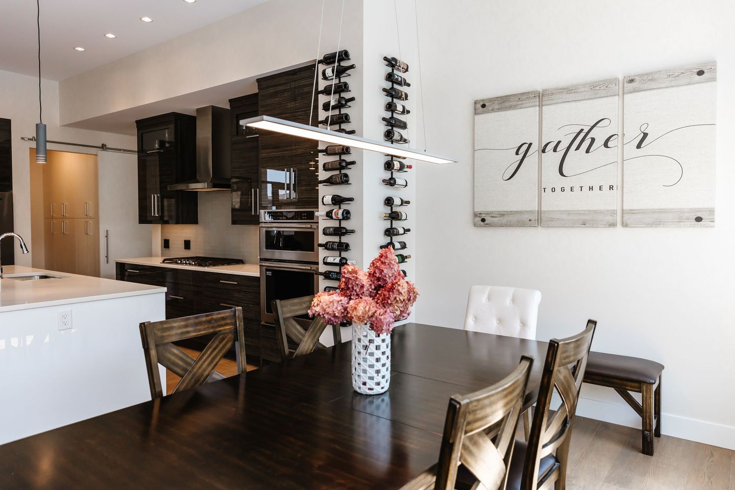 Contemporary dining area with pendant lighting and wooden cross-back chairs.