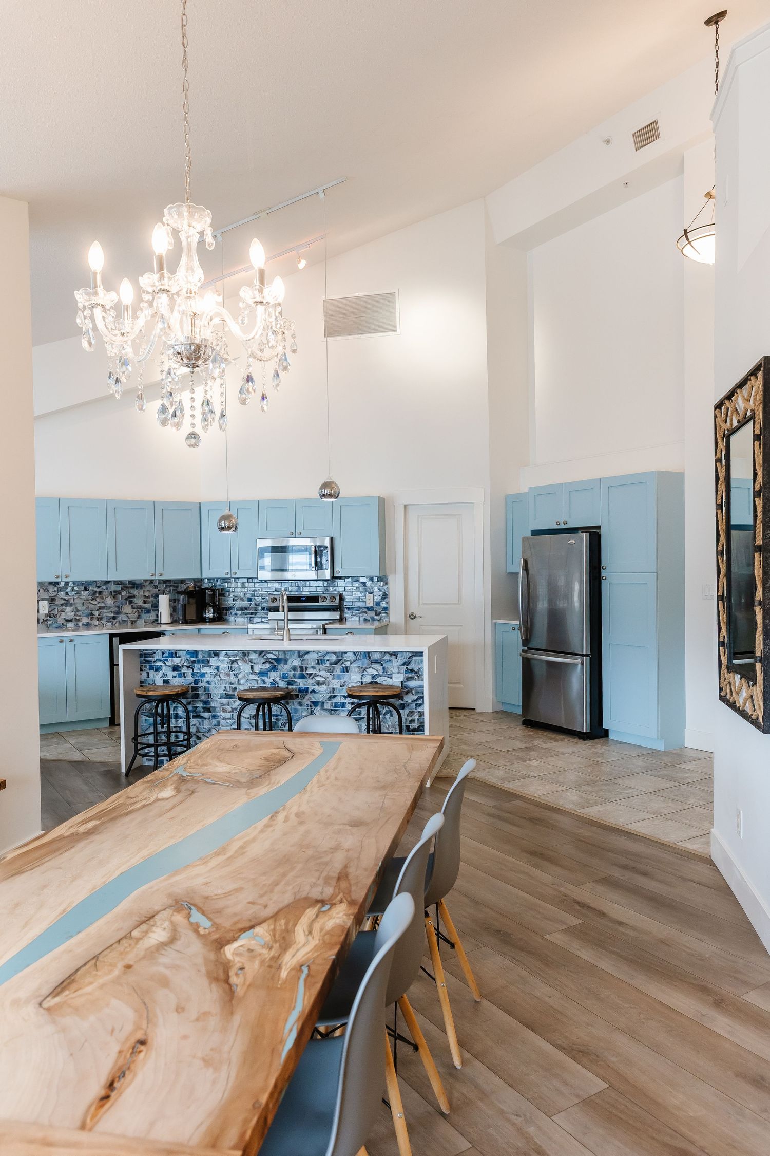 Dining area with live edge wood table and crystal chandeliers in an open floor plan in a west Kelowna Airbnb