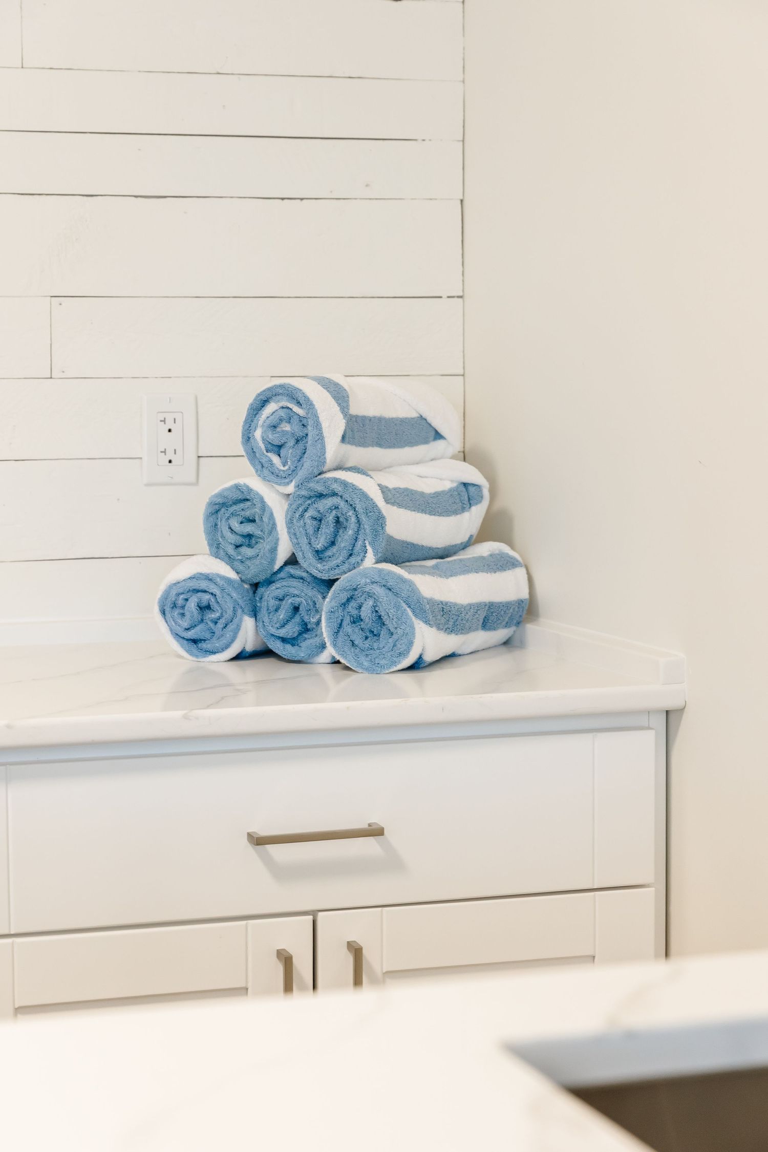 Neatly folded blue and white towels displayed on white cabinet shelving in a west Kelowna Airbnb