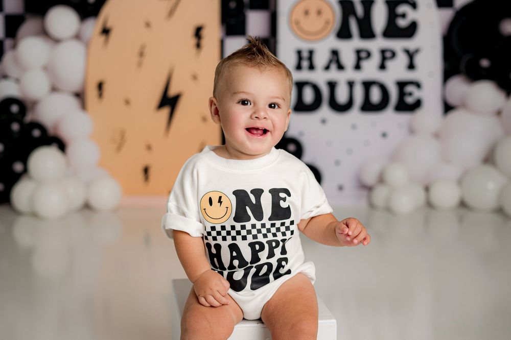 A first birthday party setup with white balloons, black and white decorations, and a smiling theme throughout the decor.