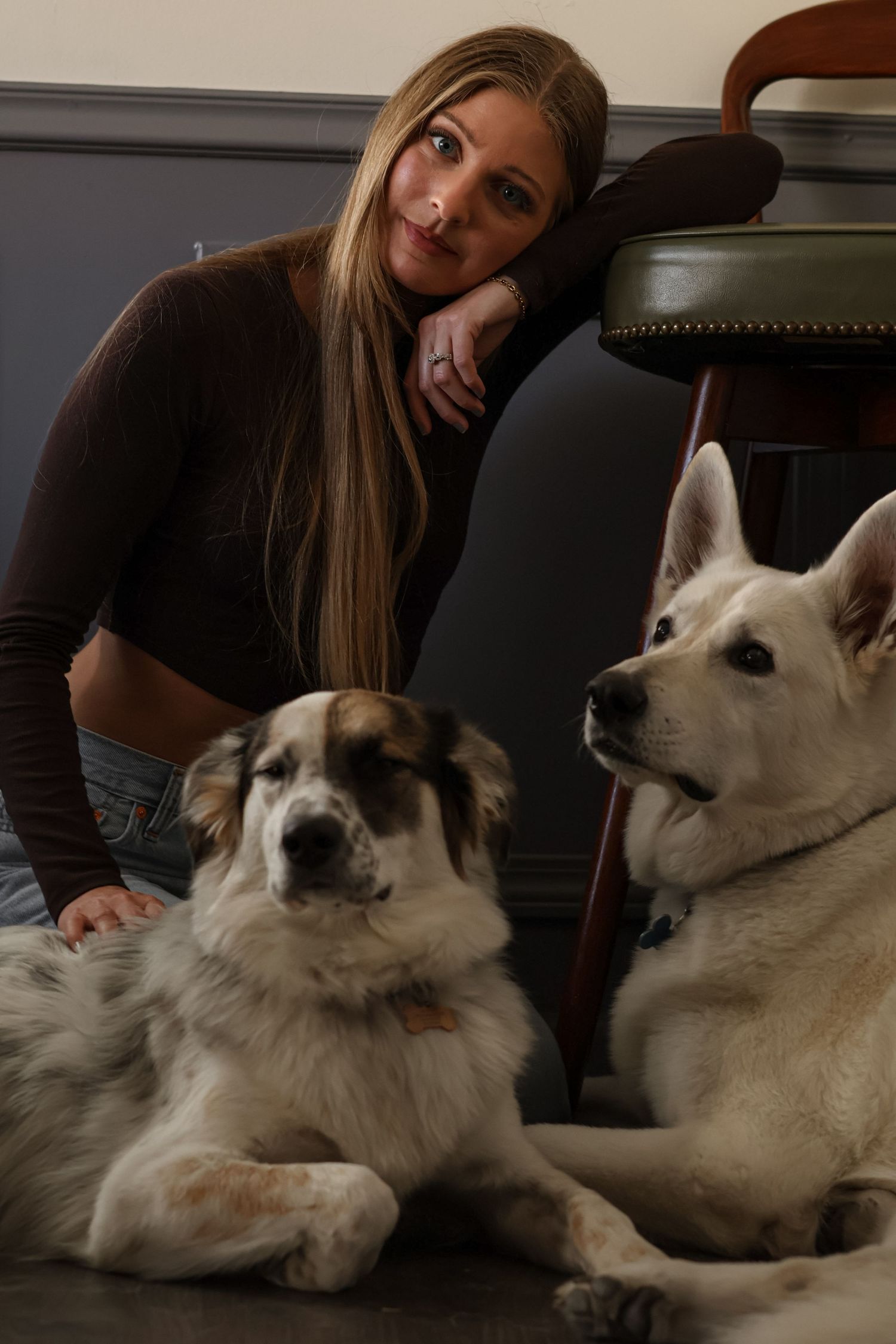 Two large dogs lounging on the floor with long-haired person in dark clothing beside them.