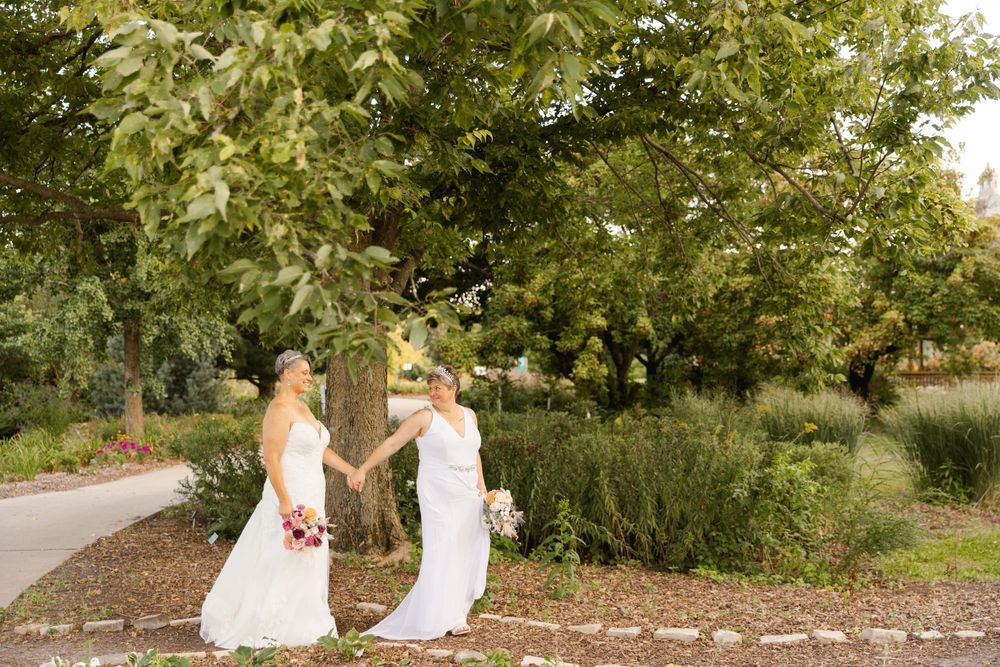 Two brides walking in garden on a fall day in Iowa. Iowa arboretum wedding venue and photography