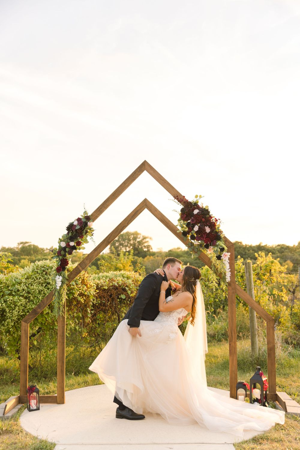 Romantic sunset wedding portraits at a vineyard with wooden arch. St. Charles, Iowa wedding venue and photography