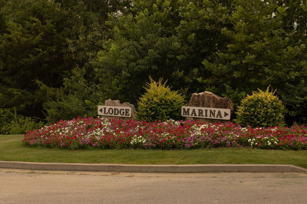 A landscaped entrance sign with 'MARINA' text surrounded by vibrant red flowers and green shrubs.