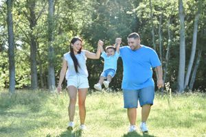 People walking together through a scenic wooded area on a sunny afternoon.