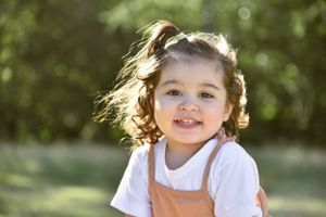 Natural outdoor photo shoot in a sunny garden setting captures genuine expressions and smiles.