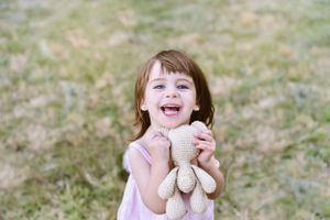 A joyful outdoor portrait session in sunlit grass shows expressions of pure happiness and laughter.