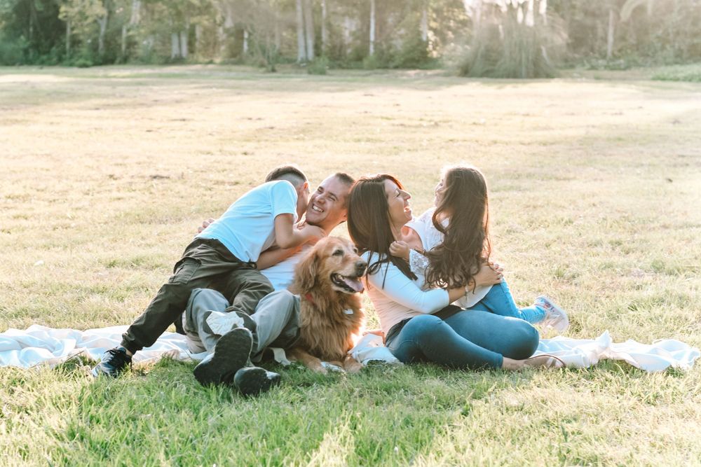 Family relaxing together on a blanket in a grassy field.