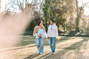 A couple walks hand in hand through a sun-drenched park path on a warm autumn afternoon.