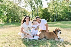 Summer family photoshoot in a sunlit park with natural greenery background.