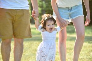 Casual family gathering on grass shows legs and playful interactions in summer sunlight.