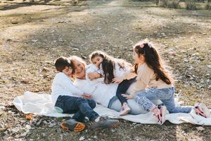 Group of friends enjoying a casual picnic on a white blanket in a natural outdoor setting.