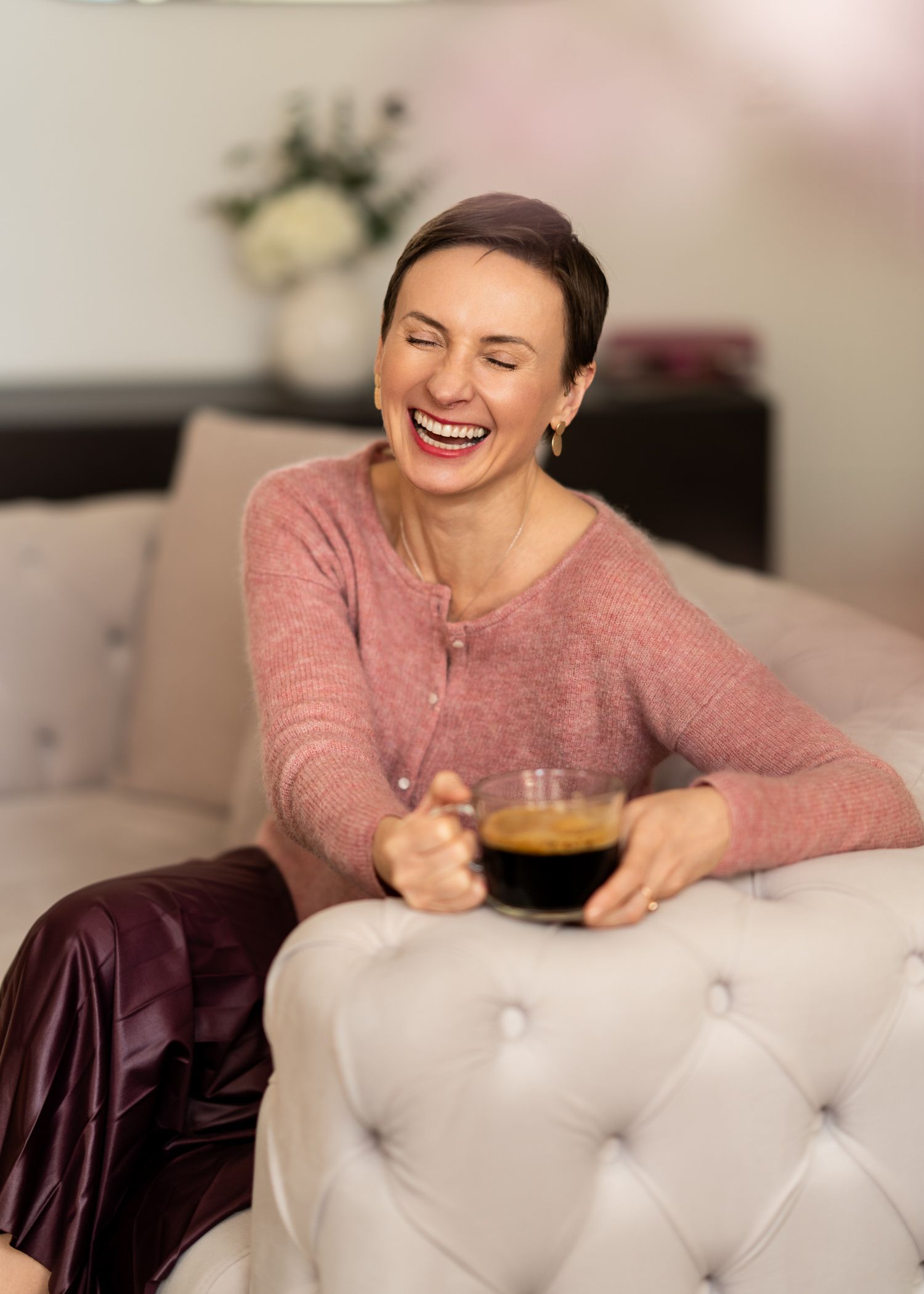 Candid lifestyle photo enjoying coffee on plush white tufted couch.