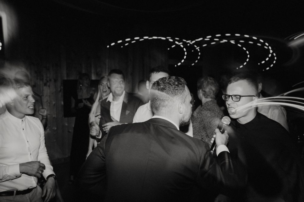 Guests celebrating on a dance floor with decorative string lights in the background.
