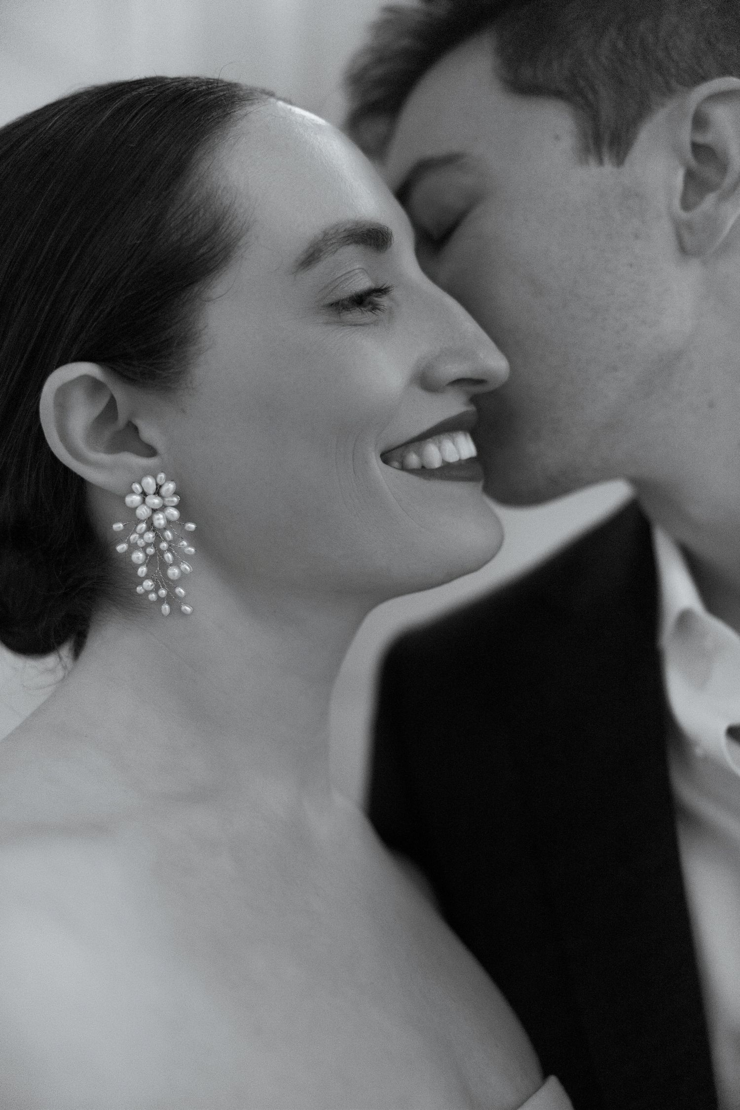 A romantic black and white wedding photo showing an intimate moment with the bride wearing sparkling drop earrings.