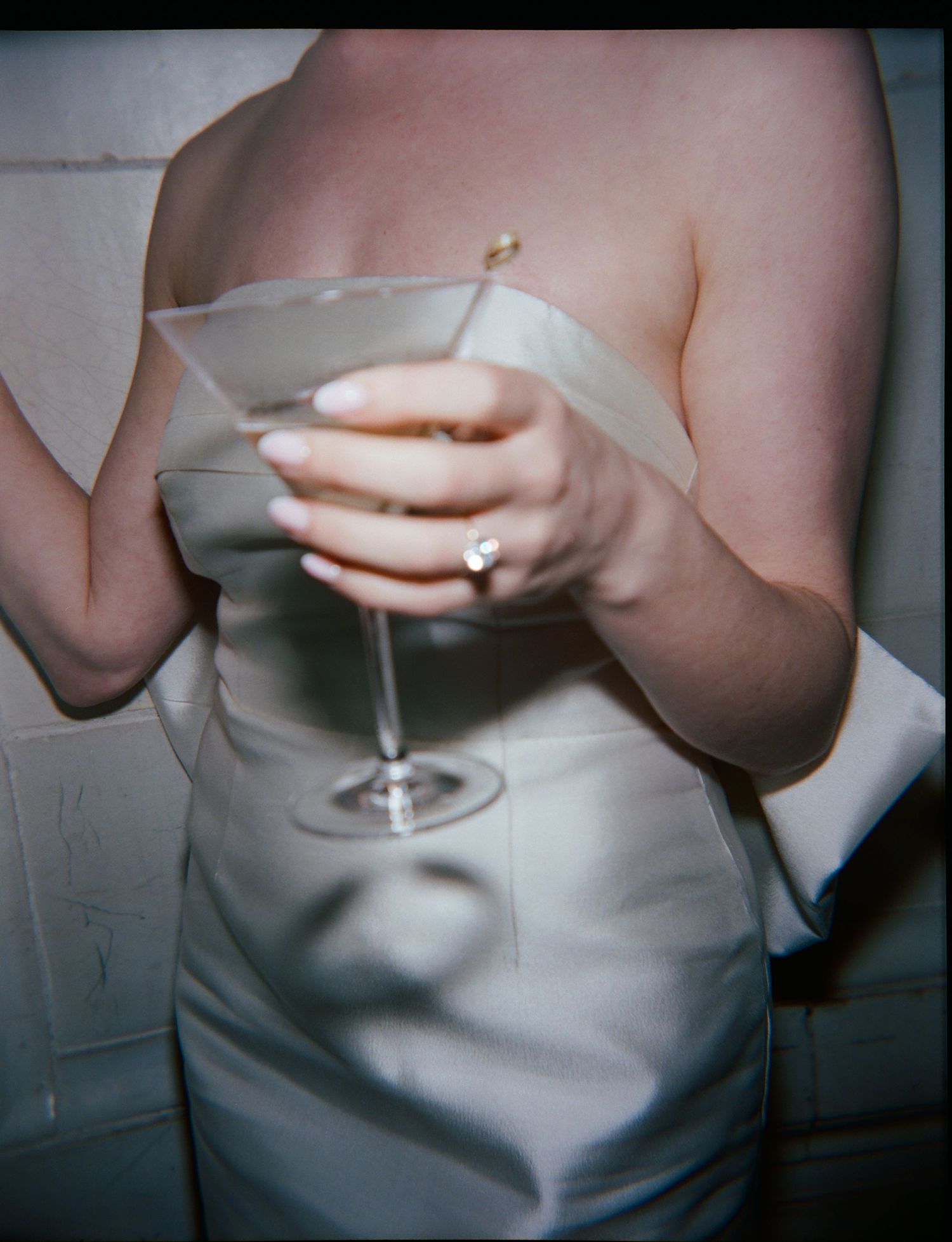 A bride in a white dress holding a martini glass at an elegant rehearsal dinner.