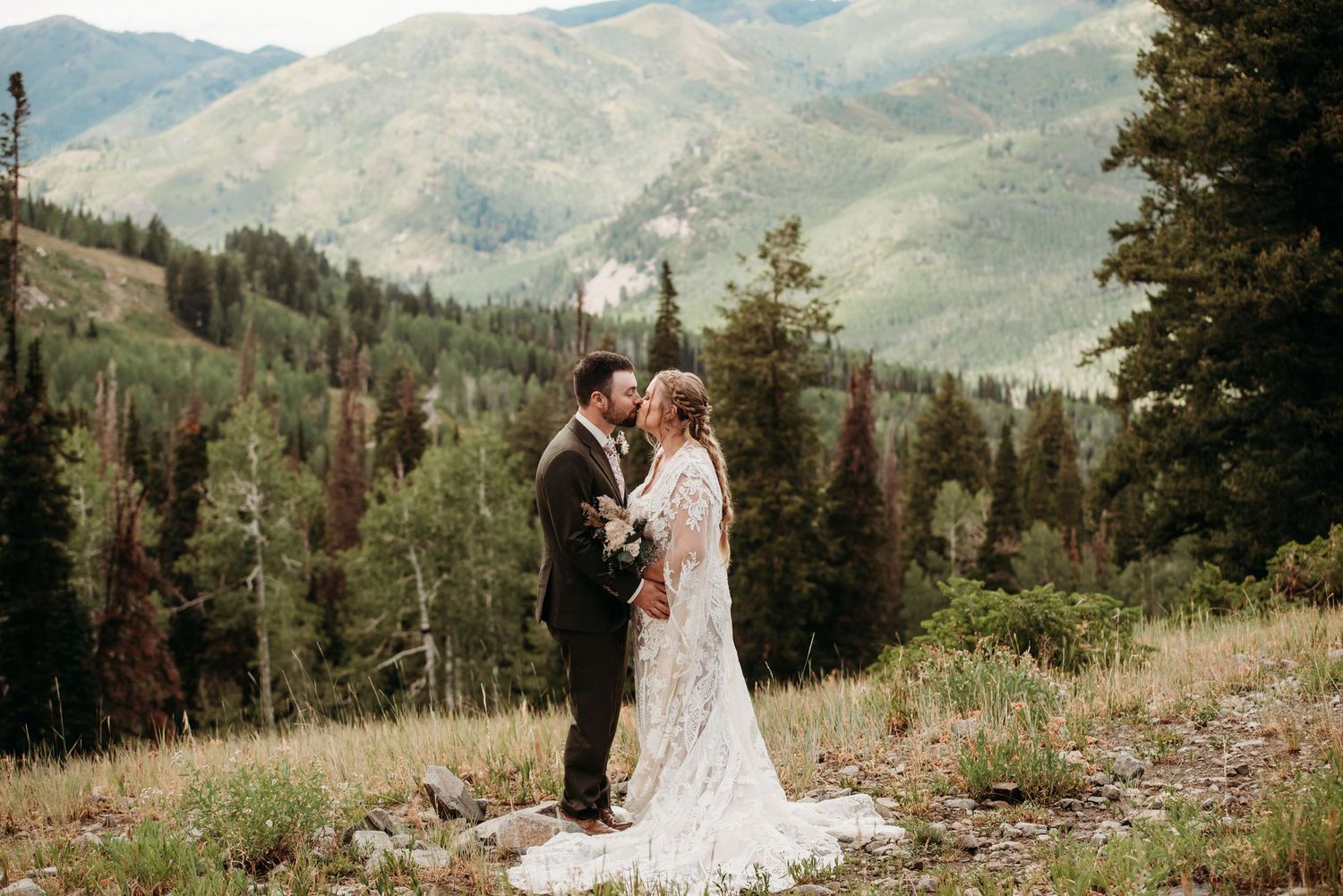 Wedding couple in scenic mountain landscape with evergreen forest.