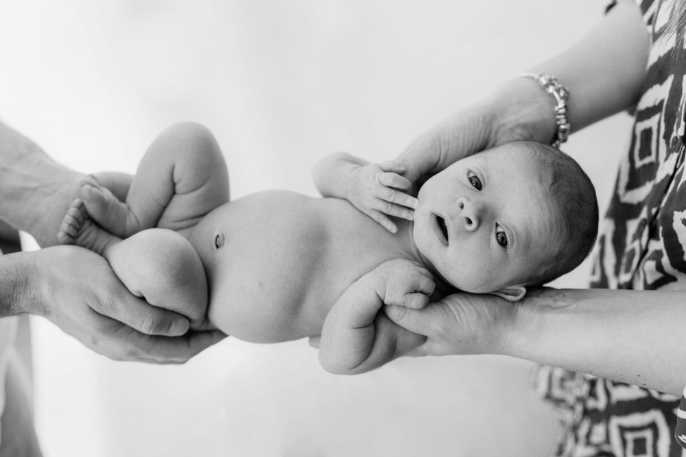 Black and white portrait of newborn baby lying on back during professional photoshoot.