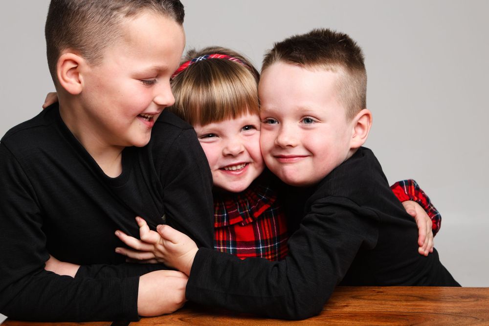 Family portrait of three in black and red outfits posing together.