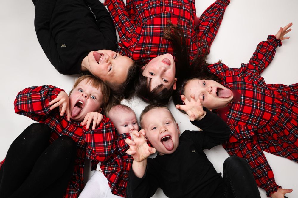 Group lying in circular formation wearing matching plaid and black outfits.