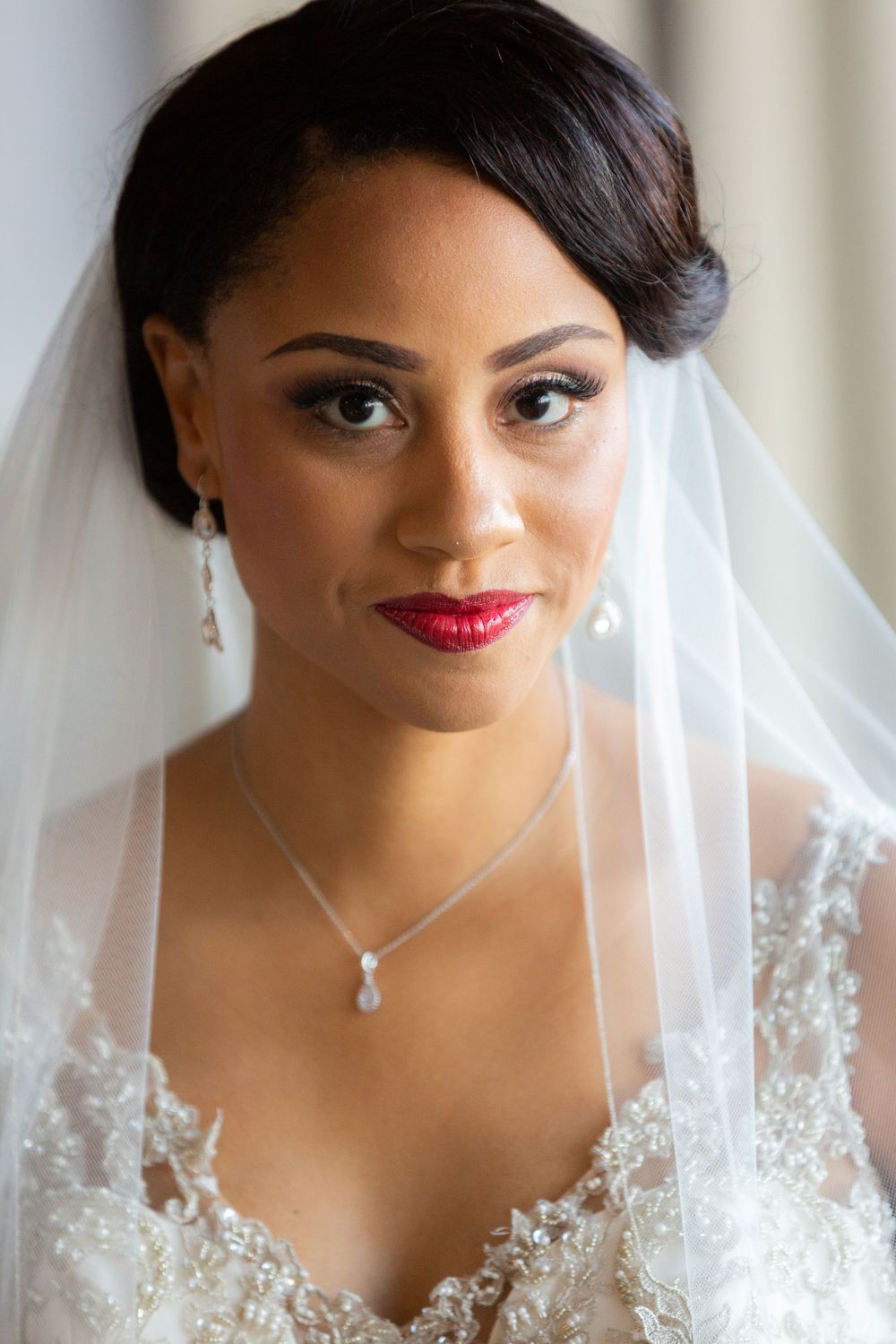 Close up portrait shot of bride wearing delicate veil and pearl jewelry.