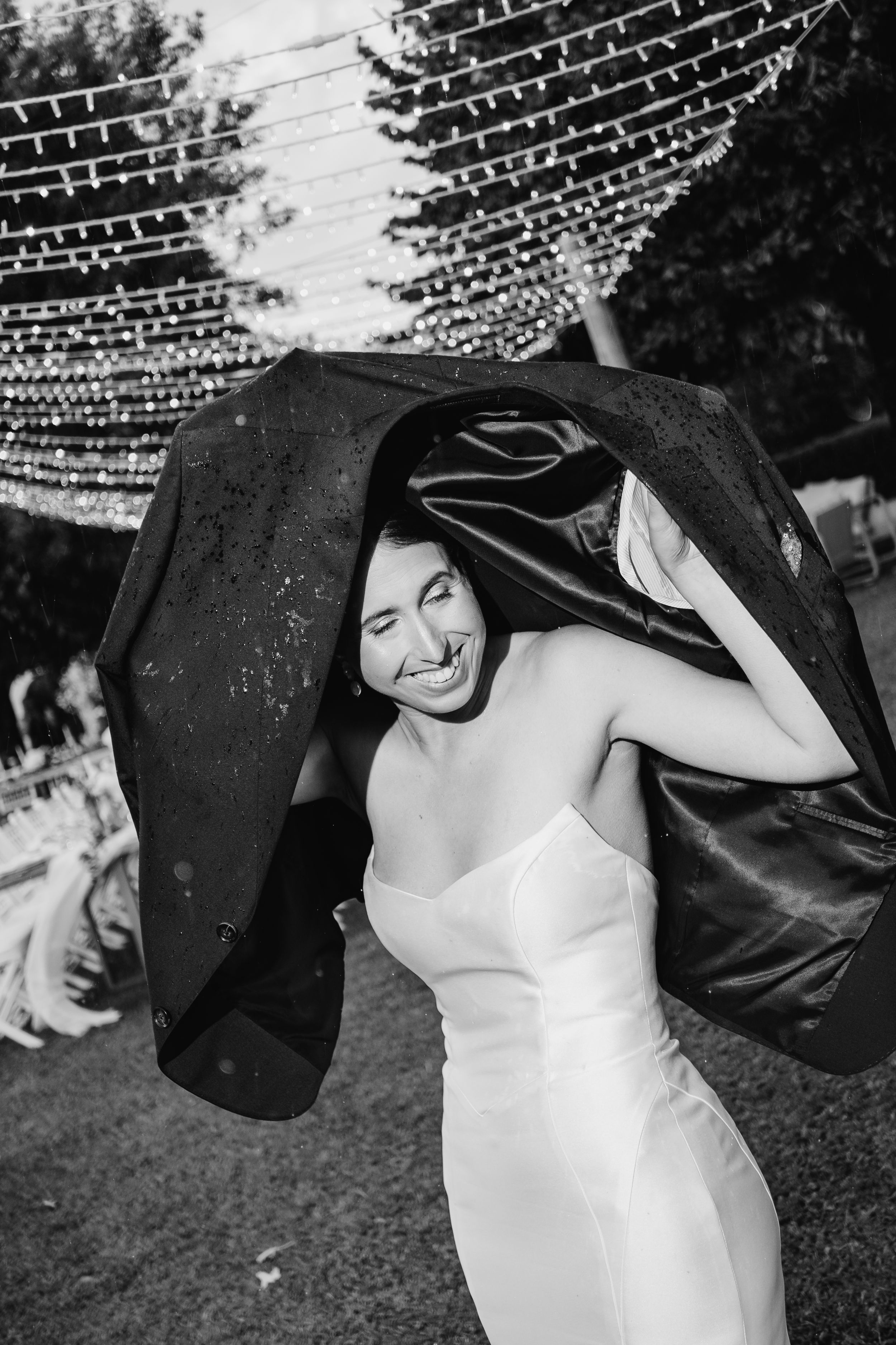 Casamento ao ar livre sob a chuva, captado em preto e branco com luzes e elegância dignas de revista.