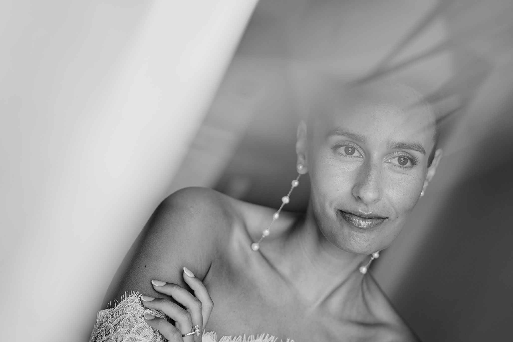 Black and white portrait of an elegant woman with dangling earrings, gazing softly at the camera.