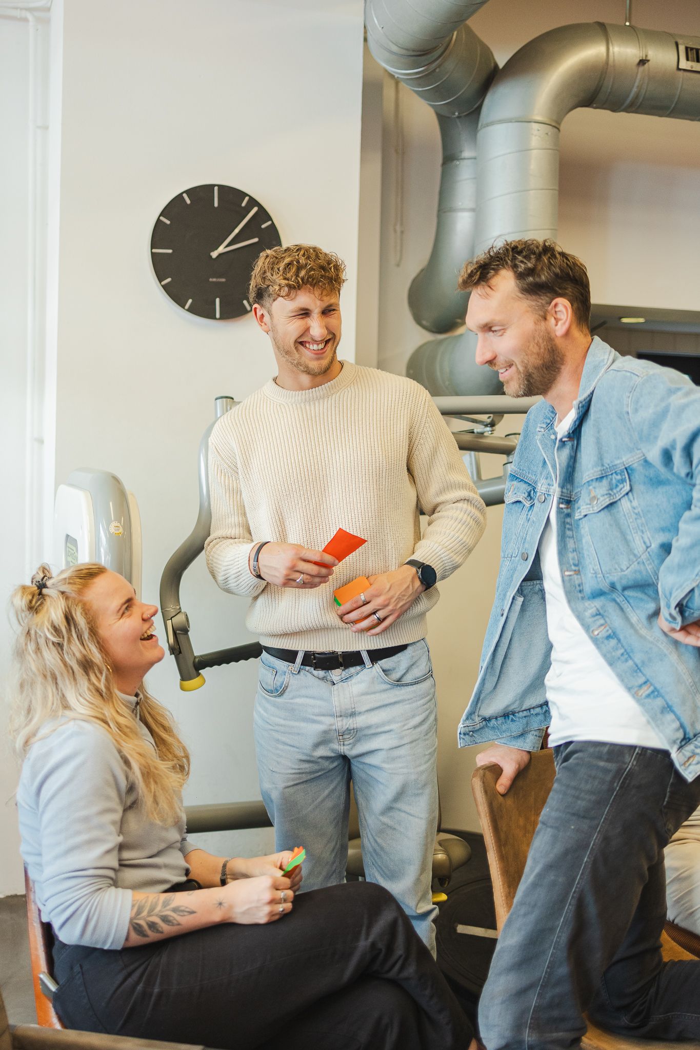 Coworkers sharing a lighthearted moment while sitting and standing in an office space.