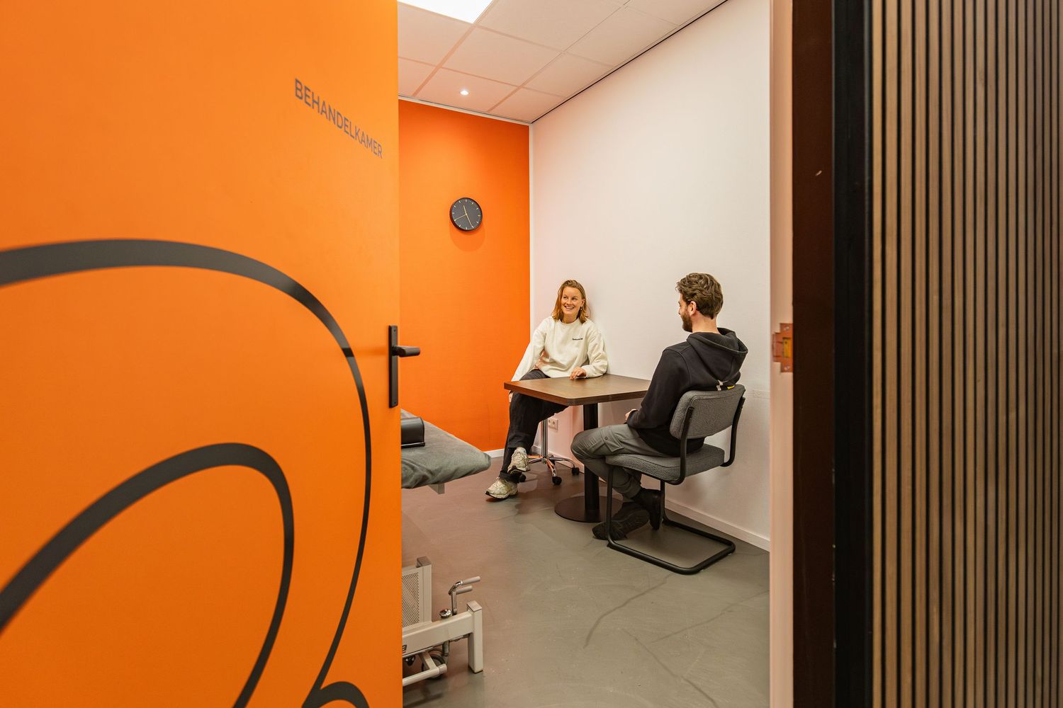 Modern office interior with bright orange walls, vertical wood slat panels, and contemporary minimalist design elements.