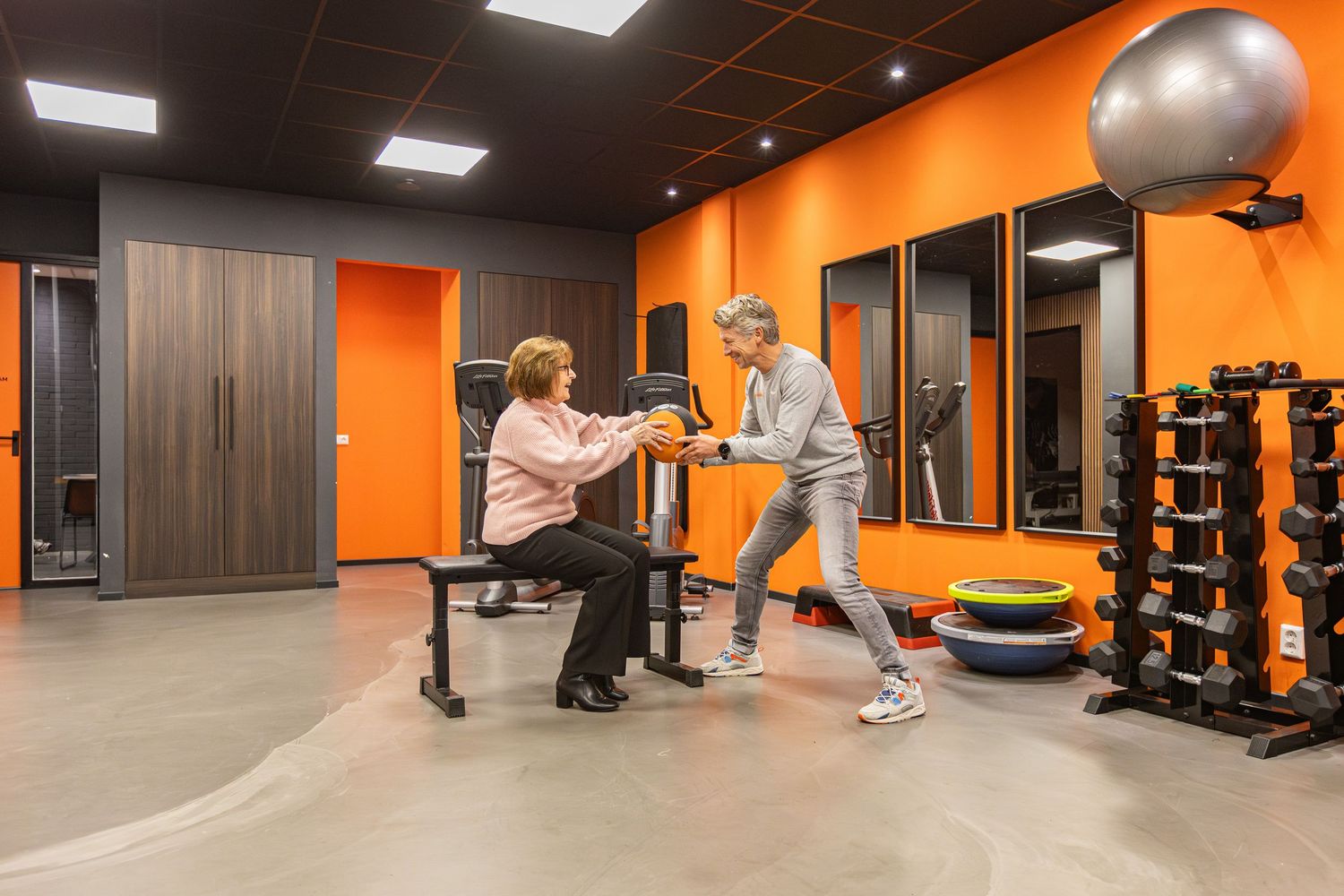 Modern fitness facility with orange walls features exercise equipment and training areas in a clean, well-lit space.