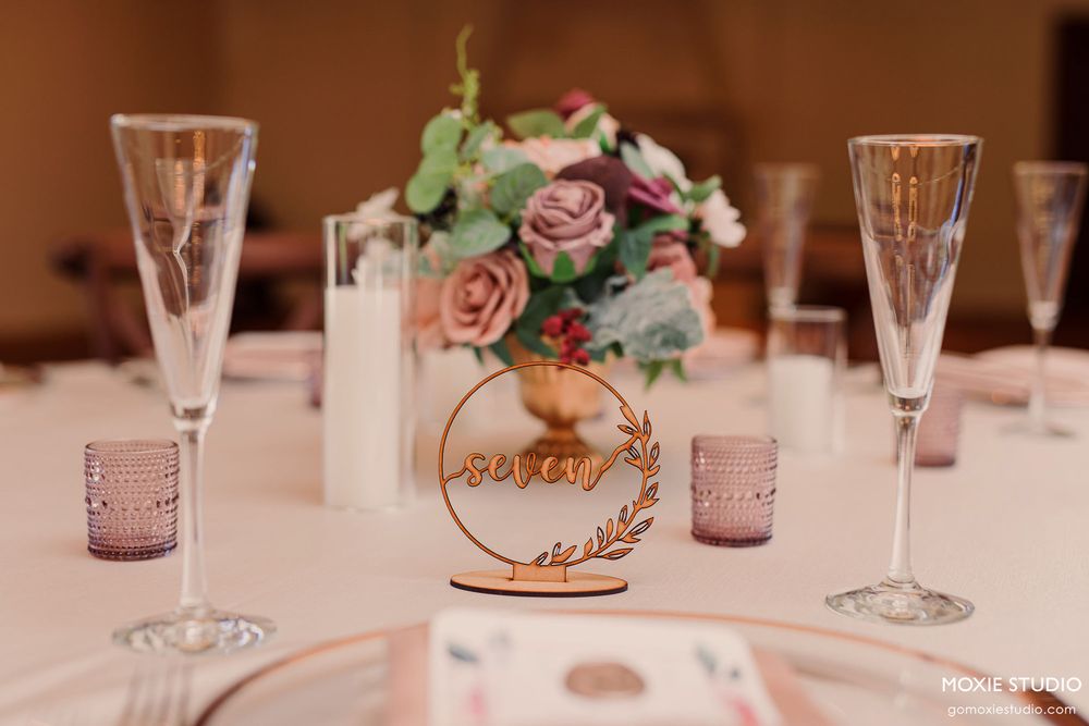 Elegant table settings with crystal wine glasses and delicate pink floral centerpieces at a formal event.