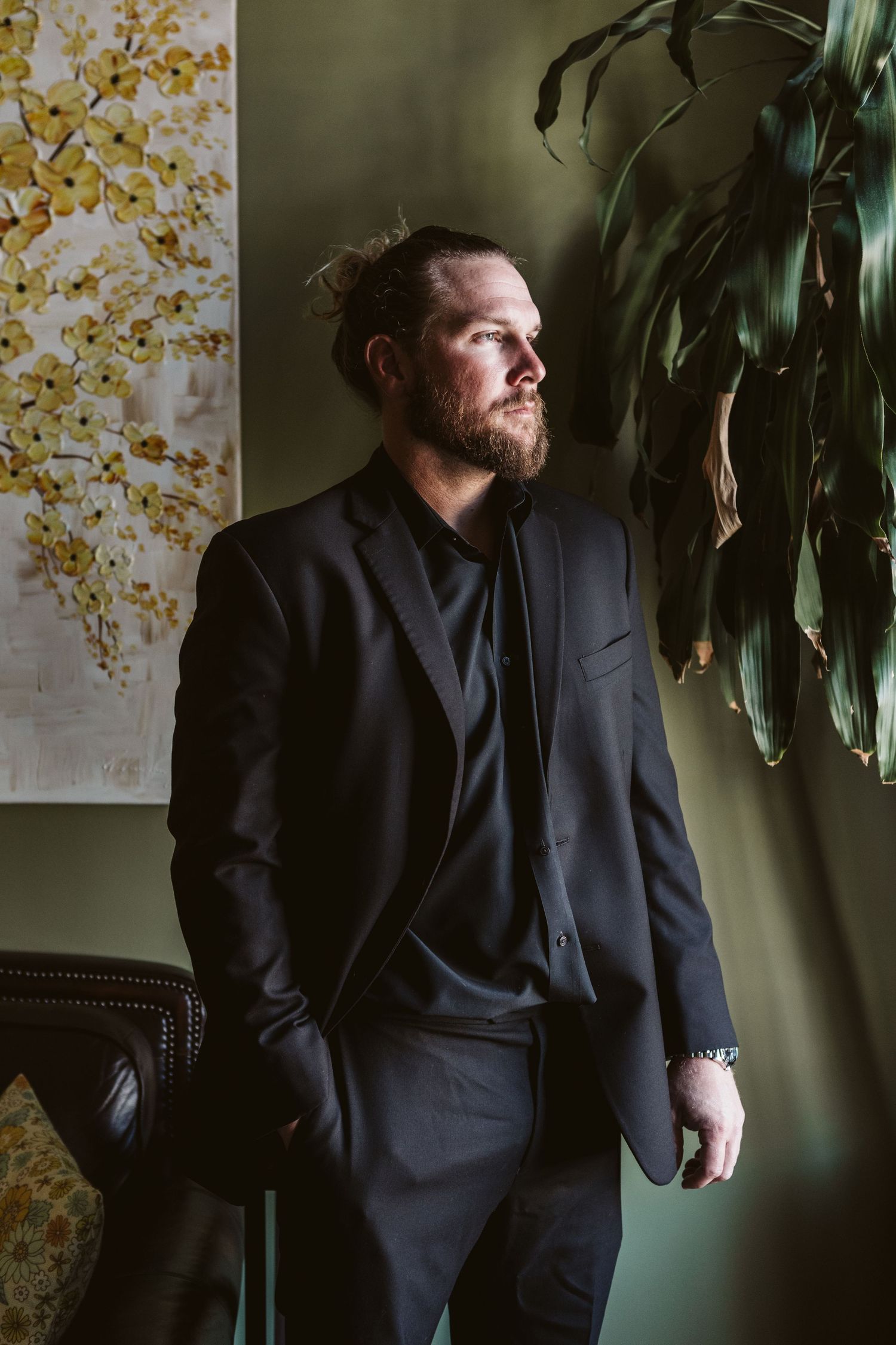 Artistic portrait series in dark tones with decorative plants and wallpaper background.