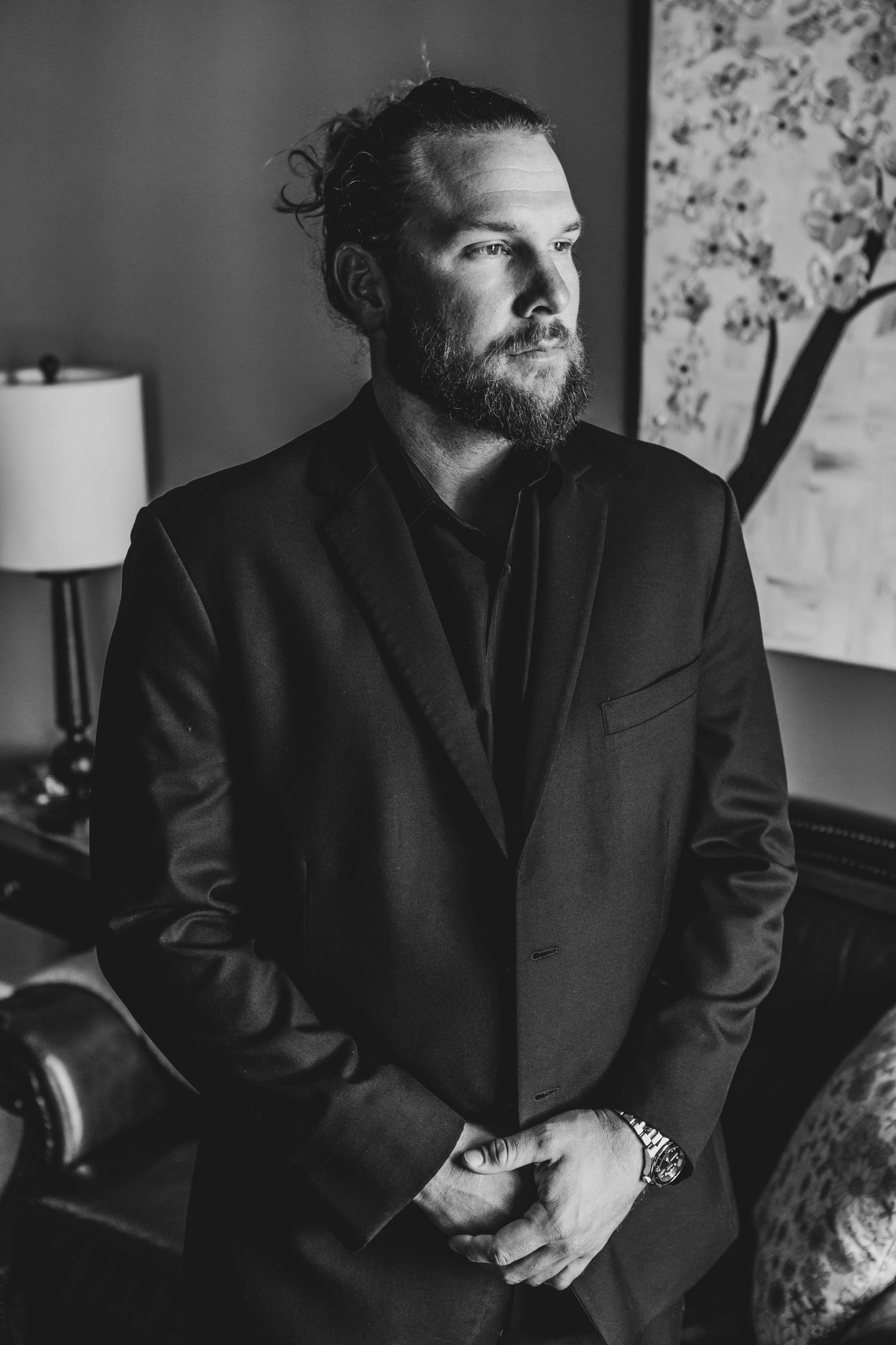 Black and white portraits in formal attire against floral wallpaper background.