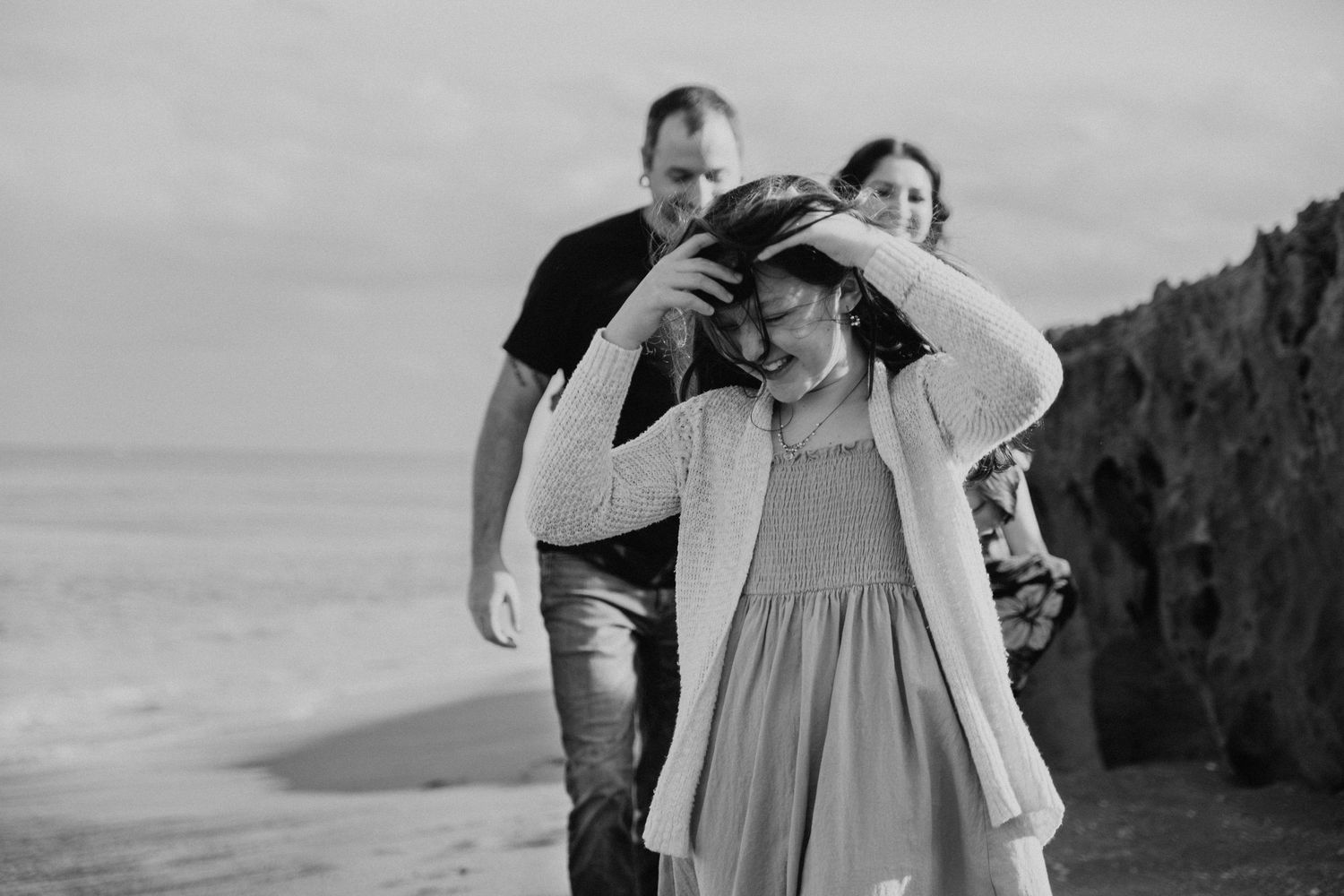 A couple in formal attire shares a romantic moment together on a beach at sunset.