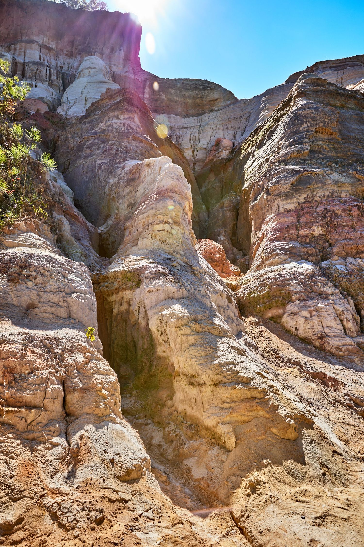 Dramatic rock formations with layered sedimentary patterns carved by erosion under bright sunlight.