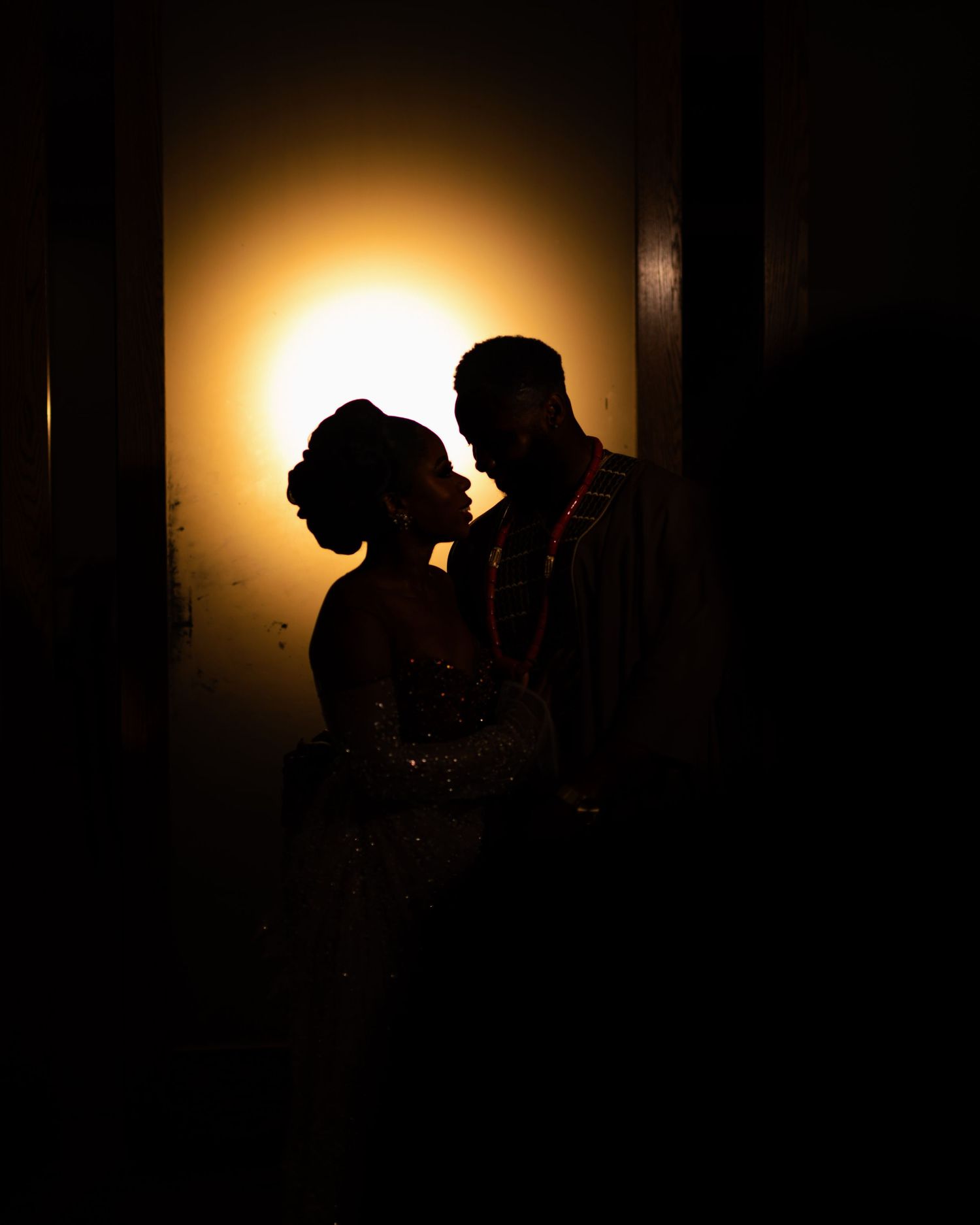 A romantic silhouette of a couple against a glowing amber background creating dramatic lighting.