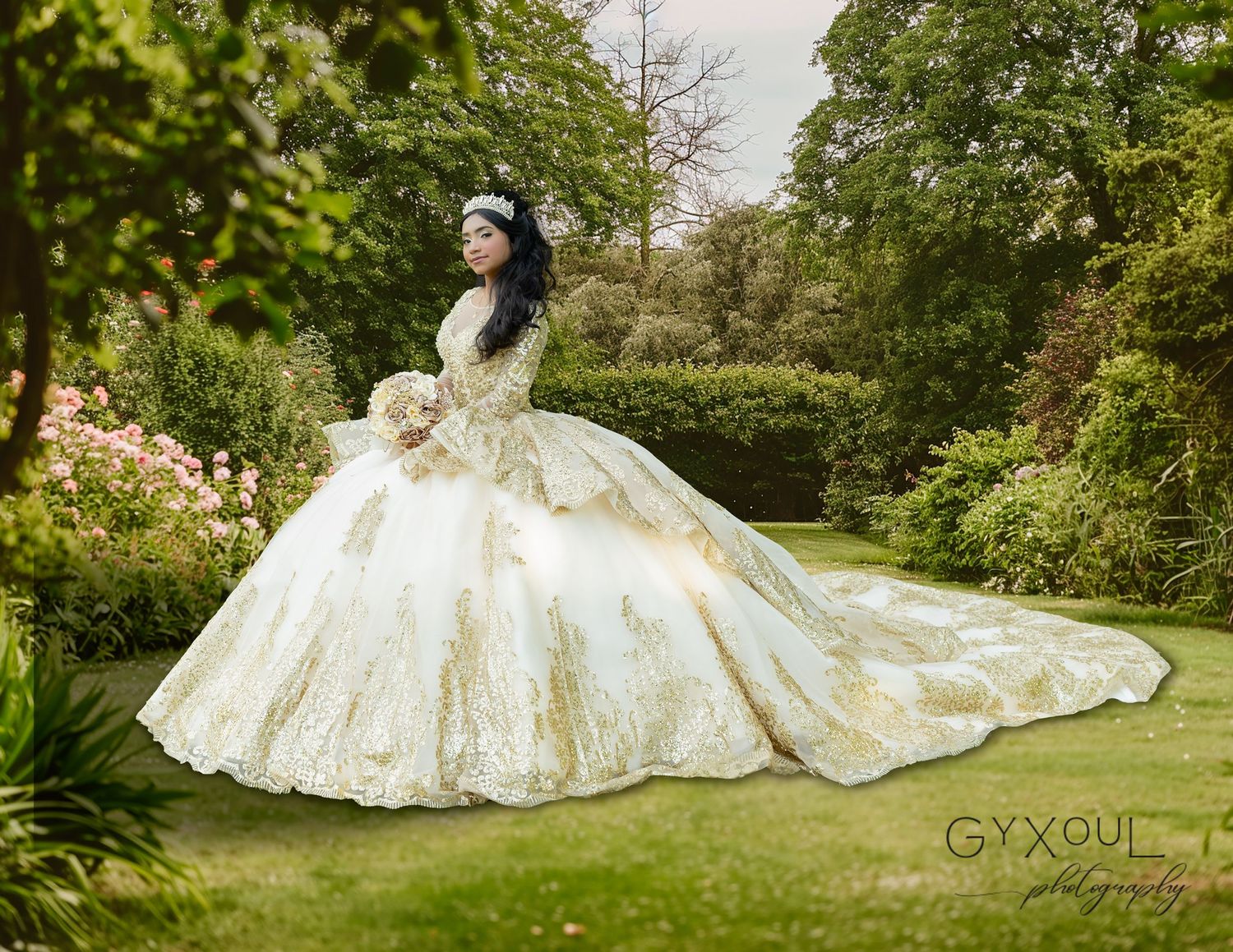 A romantic garden portrait showcasing an elaborate cream ballgown with detailed lace and long train.