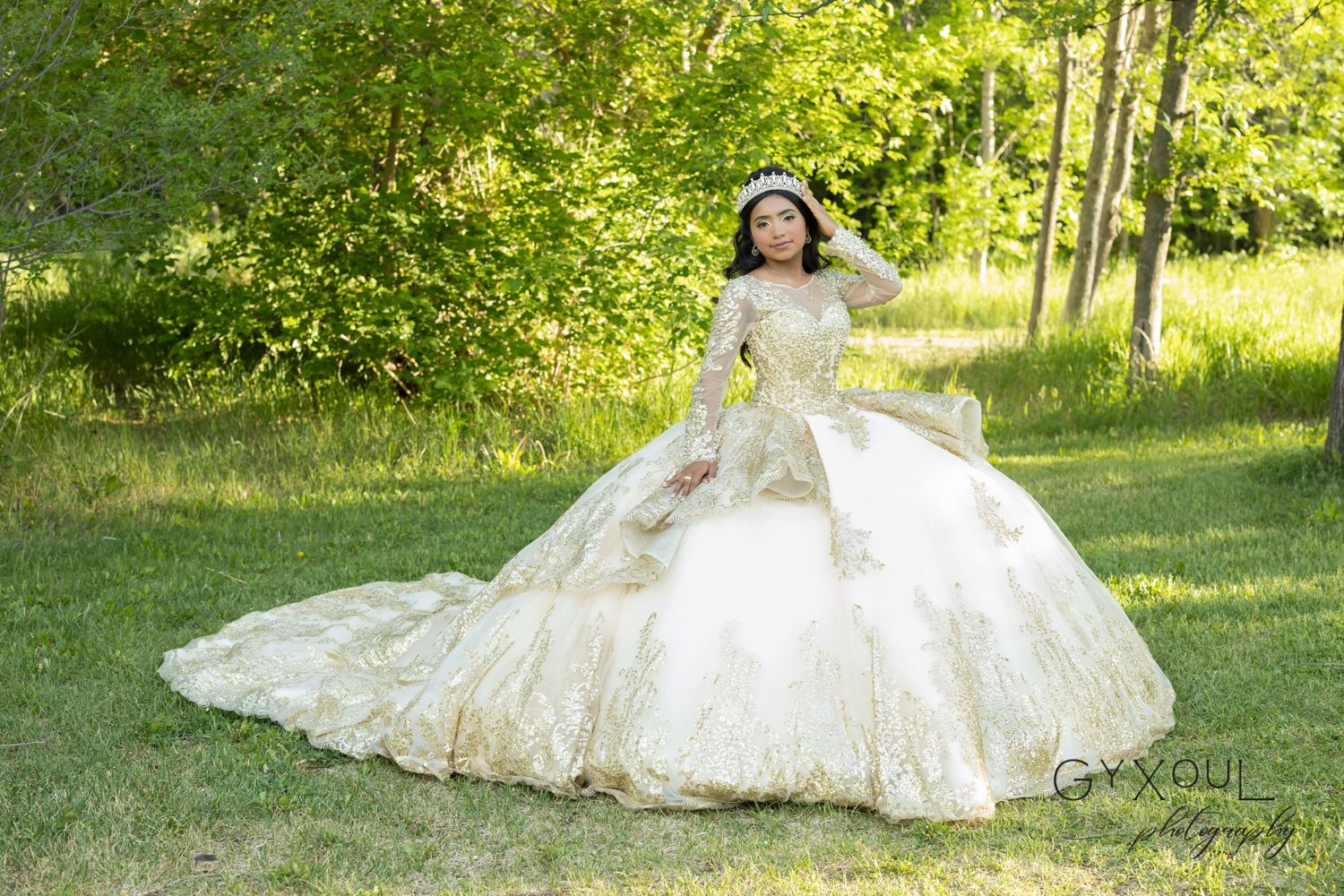 A joyful outdoor portrait featuring a luxurious cream-colored ballgown with delicate lace details in a sunlit garden.