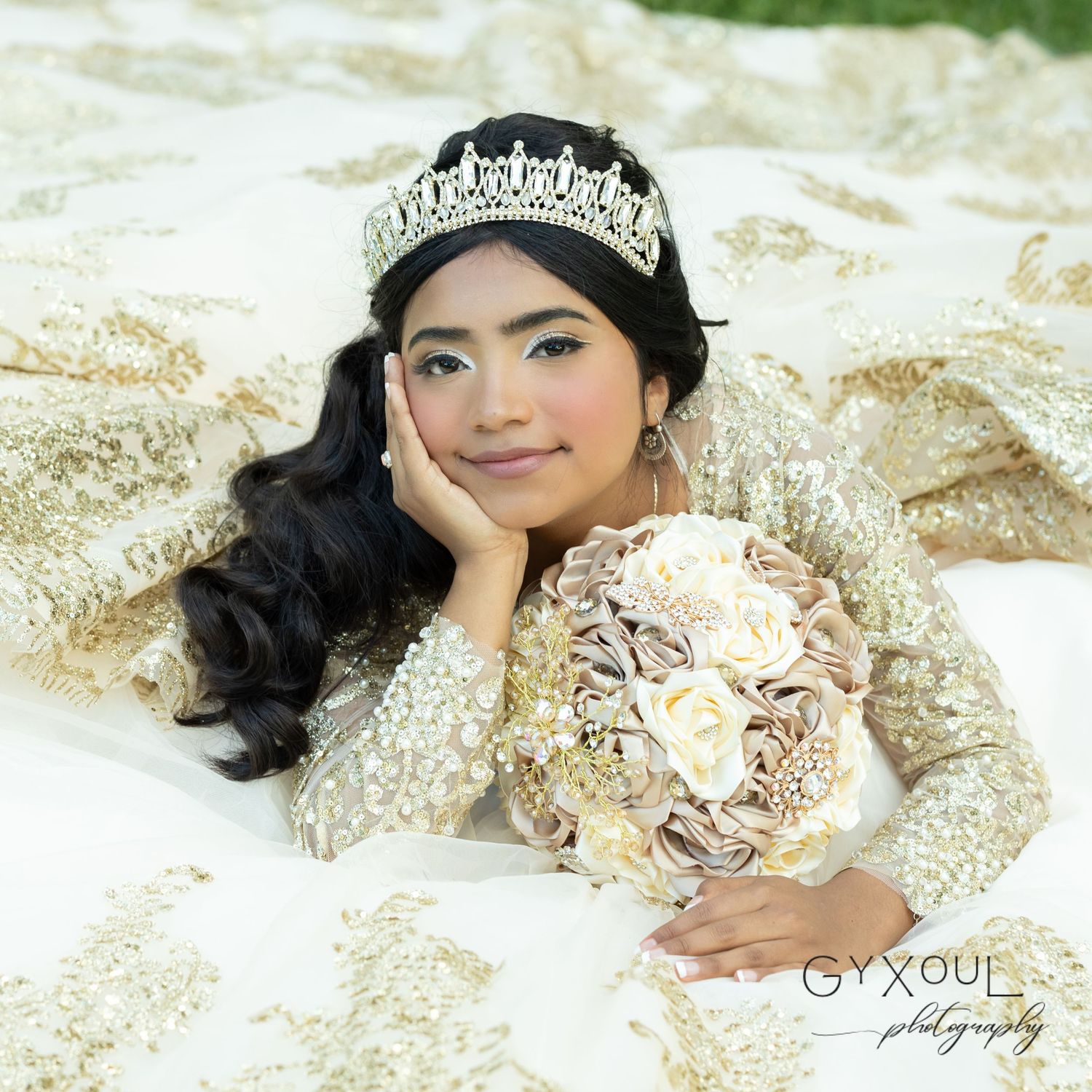 A regal quinceañera portrait featuring an ornate gold dress and matching neutral bouquet.